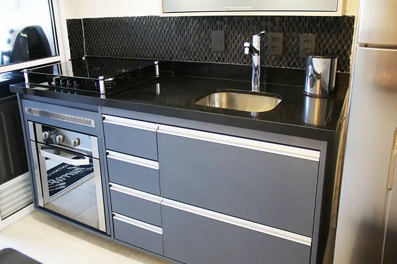 bancada de cozinha com gabinete sob medida bancada de cozinha em granito preto são gabriel, cuba embutida, monocomando deca, cooktop, forno de embutir e gabinete em marcenaria sob medida