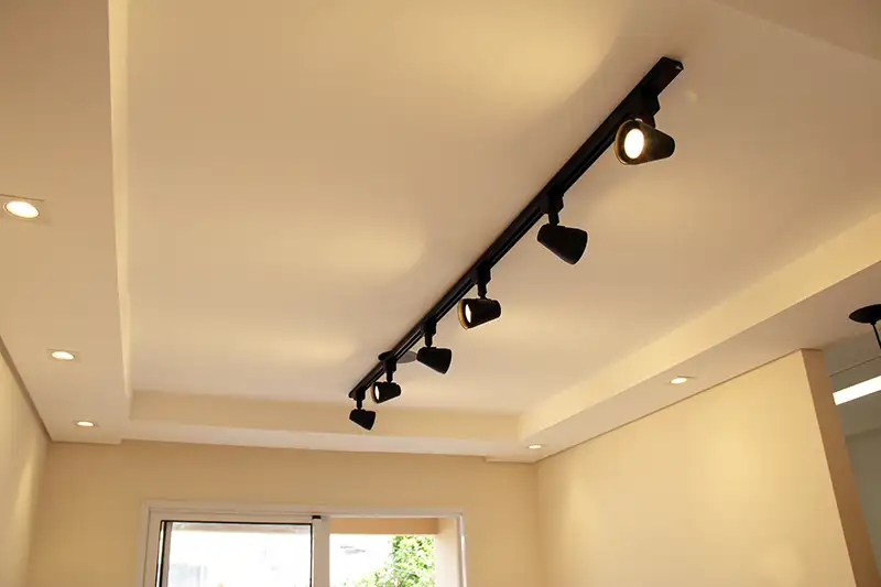 forro parcial com luminárias e trilho com spots ao centro forro de gesso parcial em sala com iluminação com trilho e spots direcionáveis