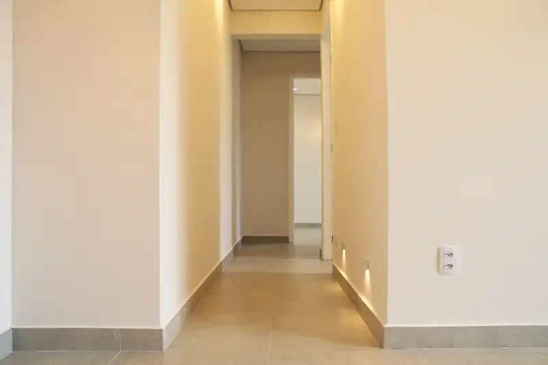 corredor com piso em porcelanato e balizadores corredor de apartamento com piso e rodapé em porcelanato e iluminação com balizadores