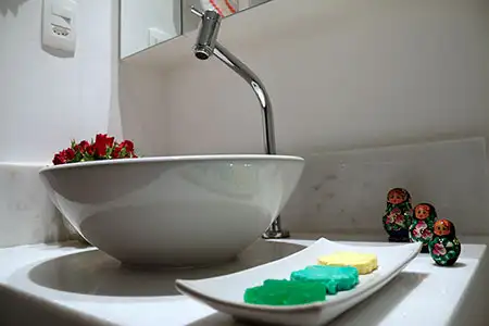 Bancada de banheiro em mármore branco com cuba de apoio em louça e torneira com bica alta Deca Bancada de banheiro em mármore branco com cuba de apoio em louça e torneira com bica alta Deca