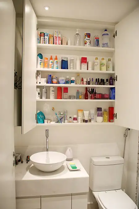 banheiro pequeno com armário alto com prateleiras com portas abertas de espelho e revestimento em formica banheiro pequeno com armário alto com prateleiras com portas abertas de espelho e revestimento em formica