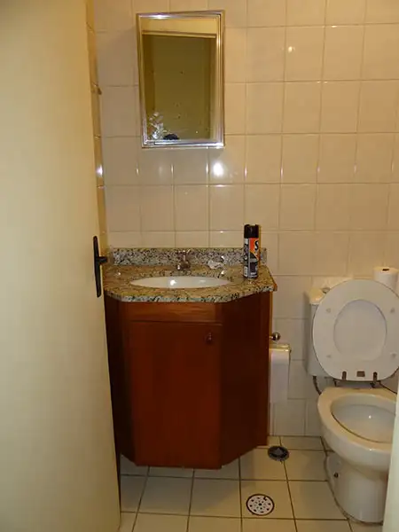 Banheiro antigo com revestimento de cerâmica, bancada em granito e móvel em madeira Banheiro antigo com revestimento de cerâmica, bancada em granito e móvel em madeira